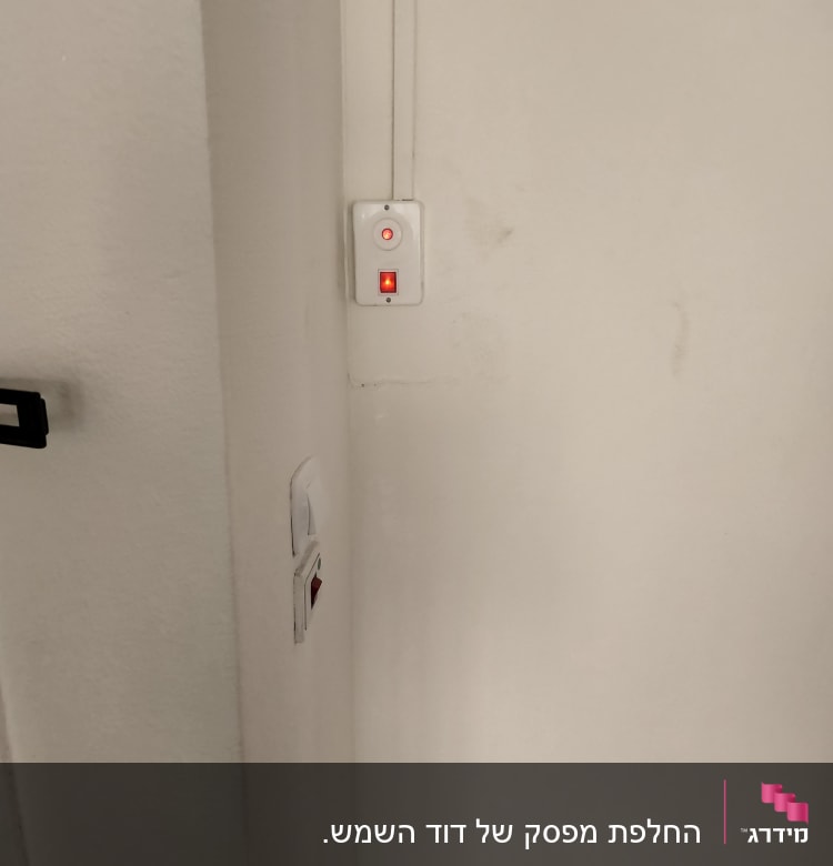 מתג דולק עם נורית חיווי אדומה על קיר לבן